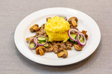 Minced beef steak with mashed potatoes and fried mushrooms is on the plate.
