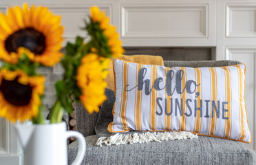 Cheerful throw pillow that says hello sunshine with sunflowers in the blurred foreground