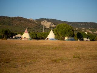 Caseta de campaña de estilo tipi indio en un bosque durante la puesta de sol © David Martínez