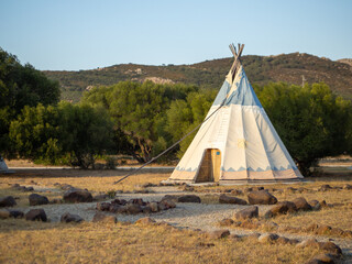 Caseta de campaña de estilo tipi indio en un bosque durante la puesta de sol