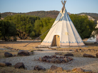 Caseta de campaña de estilo tipi indio en un bosque durante la puesta de sol