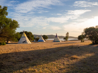 Caseta de campaña de estilo tipi indio en un bosque durante la puesta de sol