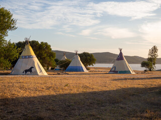 Caseta de campaña de estilo tipi indio en un bosque durante la puesta de sol