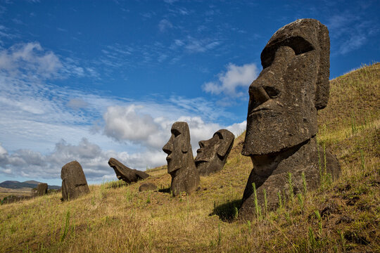 View of statues on grassy landscape against cloudy sky