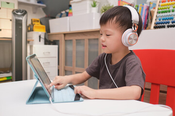 Asian 4 years old toddler boy child using tablet pc computer, Child at home during the Covid-19 health crisis, Distance Learning, Activities for Kindergarten concept