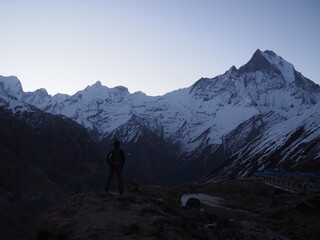 A climber standing in front of a snow-covered rock in the early morning, ABC (Annapurna Base Camp) Trek, Annapurna, Nepal