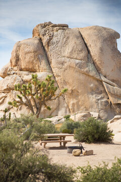 View of table and fire pit at campsite with granite rocks in background