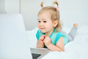 Happy smiling caucasian toddler girl playing on laptop