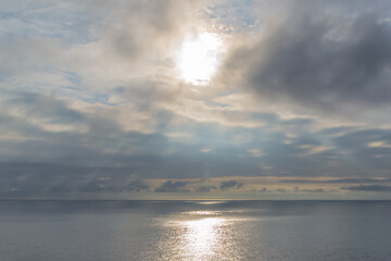 Cloudy sunset with the sun trying to get out among the clouds and reflecting on the sea