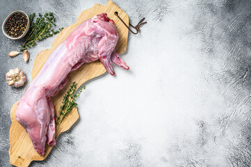 Whole raw rabbit on a cutting board. Gray background. Top view. Copy space