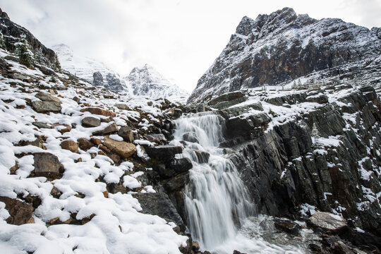 Scenic view of waterfall with snow covered mountains