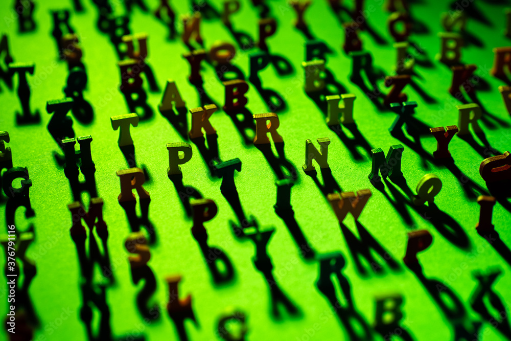 Fototapete latin letters stand on a green background and cast shadows. the letters of the alphabet in random or