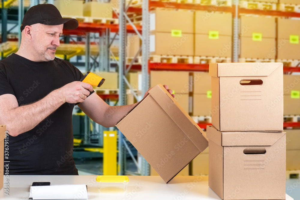 Poster working in a warehouse. a man with a barcode reader in the warehouse. preparing boxes with orders to
