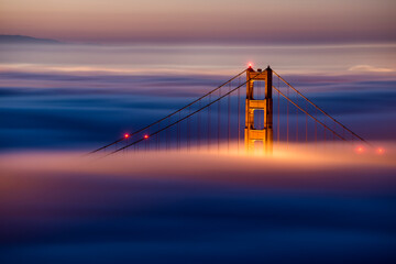 Golden Gate Bridge covered with fog during sunrise