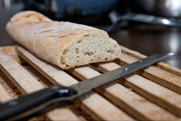 Loaf of bread cut on a wooden board with the bread knife after cutting bread.