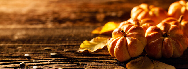 Pumpkin buns in shape of  pumpkin  and autumn leaves on  a rustic wooden background with copy space