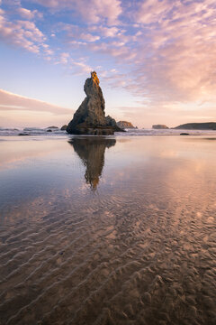 View of sea stack on Bandon Beach against cloudy sky during sunset