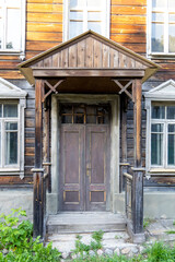 Porch of an abandoned two-story Moscow wooden house. Old wooden door with worn brown paint. Antique wooden house building