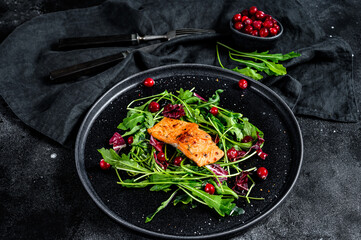 Seafood salad with salmon, arugula, lettuce and cranberries. Black background. Top view