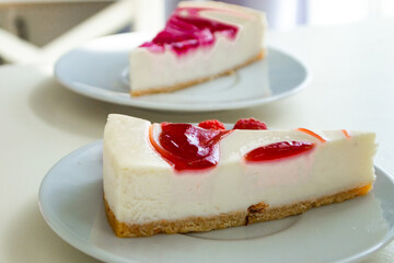 raspberry cheesecake on a white saucer in a white kitchen with natural light
