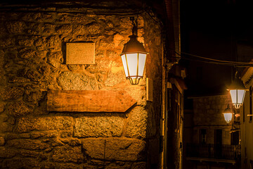 Old stone houses, old sign with indication for selling antiques, under the light of candlesticks of...