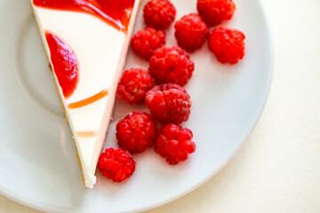 raspberry cheesecake on a white saucer in a white kitchen with natural light