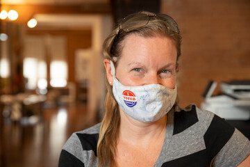 Caucasian woman wearing a mask and an I Voted Today sticker on the mask