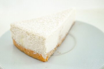Fototapeta na wymiar 1 piece of cheesecake on a white saucer on a white table on a white kitchen with natural light
