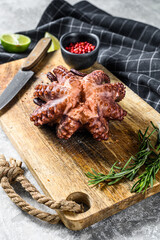 Grilled whole octopus on a cutting Board. Gray background. Top view