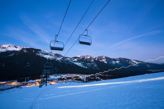 Ski lift moving over snow covered landscape at night