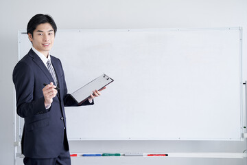 テキスト合成用、ホワイトボードでを使って説明をする日本人男性ビジネスマン