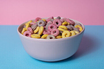Isolated bowl of mixed cereals and marshmallows on a blue and pink background