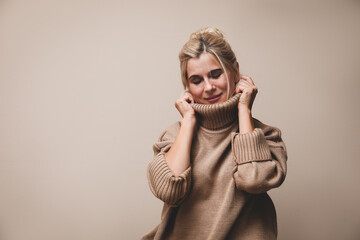 Happy woman in stylish sweater on beige background. Space for text
