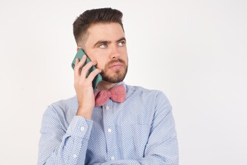 Sad brunette caucasian man in red shirt talking on smartphone. Communication concept.