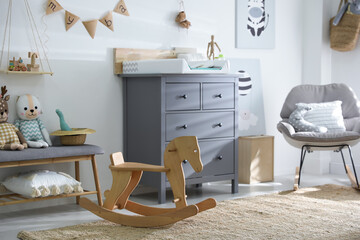 Beautiful baby room interior with toys, rocking chair and modern changing table