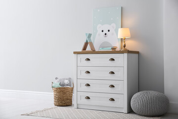 Modern white chest of drawers near light wall in child room. Interior design