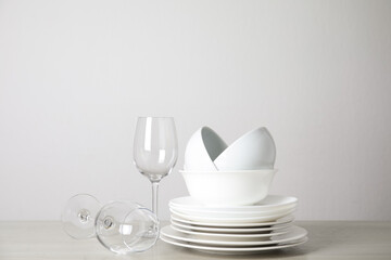 Clean plates, bowls and glasses on table against white background. Space for text