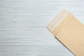 Kraft paper envelope on white wooden background, top view. Space for text