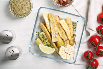 Flat lay composition with raw cut white carrot in baking dish on wooden table