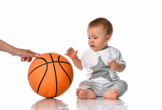 Baby boy and mother hand passing basketball ball