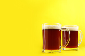 Delicious homemade kvass in glass mugs on yellow background. Space for text
