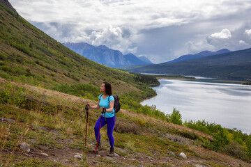 Naklejka premium Adventurous Girl Hiking up the Nares Mountain during a cloudy and sunny evening. Taken at Carcross, near Whitehorse, Yukon, Canada.