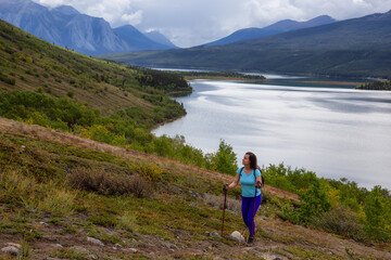 Adventurous Girl Hiking up the Nares Mountain during a cloudy and sunny evening. Taken at Carcross, near Whitehorse, Yukon, Canada.