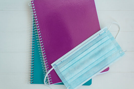 Top view of notebooks and medical mask. Back to school during covid-19 pandemic, new normal concept