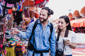 Obraz na płótnie Canvas Latin couple backpacker shopping in a Tourist Market in Mexico City, Mexican Traveler in Latin America