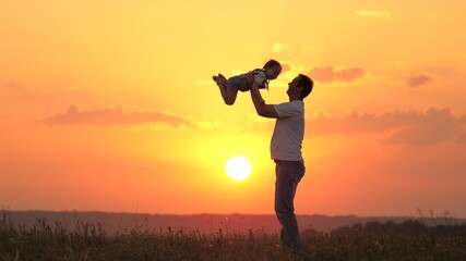 dad plays with his little daughter, joyfully throws child into the sky. happy family in nature. dad and child. family resting at sunset in the field. happy healthy family walking in the fresh air.