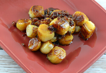 Fresh scallops cooked with brown sugar bacon sauce on red serving platter