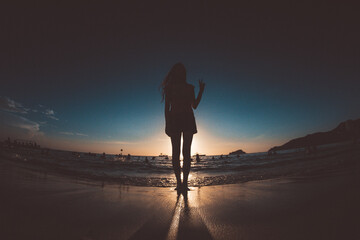 Fototapeta na wymiar silhouette of a woman walking on the beach