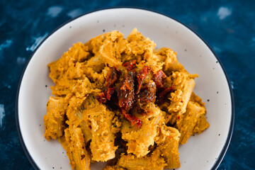plant-based food, vegan maccheroni pasta with hummus based sauce and sundried tomatoes