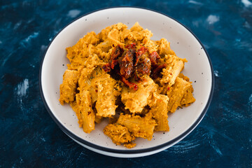plant-based food, vegan maccheroni pasta with hummus based sauce and sundried tomatoes